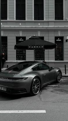 a grey sports car parked in front of a building