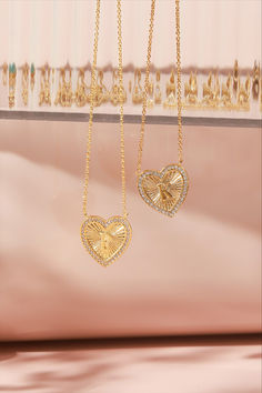 Two gold vintage-inspired heart initial necklaces with an intricate textured pattern and surrounded by small crystals. One heart displays the initial 'P' and the other 'K,' both suspended on a gold chain against a soft pink backdrop. Heart Cut Initials Jewelry Gift, Gold Heart Pendant Necklace With Initials, Open Heart Initials Jewelry For Anniversary, Gold Open Heart Necklace With Initials, Gold Heart Initial Necklace For Anniversary, Gold Heart Necklace With Initial Pendant For Anniversary, Gold Heart Necklace With Initials, Heart Cut Jewelry With Initials For Valentine's Day, Gold Initial Necklace With Heart Pendant For Anniversary