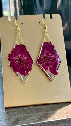 a pair of pink flower earrings sitting on top of a table