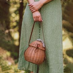 a woman in a green dress holding a wicker purse