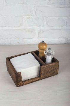 a wooden box with napkins and salt and pepper shakers in it on a table