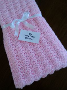 a pink crocheted blanket with a name tag on it that says, my very yarn blanket