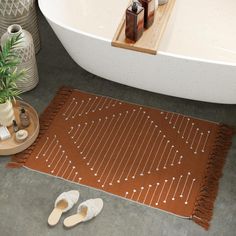 a pair of slippers sitting on top of a rug next to a bath tub