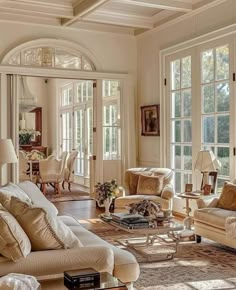 a living room filled with lots of furniture next to large windows and french doors on the wall