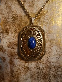 This stunning gold plated locket features a cobalt blue stone in the center and can fit 2 photos inside. It is in excellent condition. Measurements- Bail to end of pendant: 2.5 inches Width: 1.5 inches Chain: 14 inches *ALL ITEMS ARE FINAL SALE AND COME FROM A SMOKE FREE HOME. ITEMS MAY HAVE SCUFFS, ODOR STAINS/MARKS OR HOLES. I DO NOT INSPECT ANY ITEMS SOLD UNLESS INDICATED IN PHOTOS OR DESCRIPTION. ALL ITEMS ARE PURCHASED AS IS AND ARE SOLD AS IS.* Blue Brass Jewelry With Vintage Charm, Blue Brass Jewelry For Anniversary, Blue Engraved Jewelry For Keepsake, Blue Oval Locket Necklace, Oval Blue Locket Necklace, Blue Hallmarked Medallion Jewelry, Blue Medallion Locket Necklace As Gift, Blue Medallion Jewelry For Anniversary, Blue Engraved Necklace For Keepsake