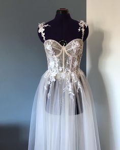 "This wedding corset dress \"Lila\" based on a corset top is made of lace with sequins and soft tulle in different shades. In this bridal dress, the cups are transparent, but it is possible to make them opaque, it is also possible to add a satin skirt so that it is not so transparent, there is a slit in the front. corset and cups are decorated with floral appliqués and shimmering silver beads. The dress has thin straps that are decorated with 3D flowers. If you want to see more variations of wedding dresses, go here: https://www.etsy.com/shop/ANadettaSewing?ref=shop-header-name&listing_id=1324006106§ion_id=39668269 This beach wedding dress will be custom made to your unique measurements and proportionate to your height. After ordering, I will send you a photo with a description of how to t Wedding Corset Dress, Off Shoulder Wedding Gown, Cream Wedding Dresses, Beach Bridal Dresses, Gown Floral, Wedding Corset, Beach Wedding Gown, Bridal Skirts, Transparent Dress