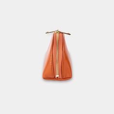 an orange handbag with gold zippers