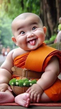 a smiling baby in an orange outfit sitting on the ground