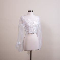 "Romantic puff sleeve lace topper | light ivory bridal lace topper | bridal lace jacket | bridal separates Light ivory wedding dress topper with built in tulle sash at the back. The color is light ivory. It is fully lined with soft tulle fabric. It features satin wrapped buttons at the back. Please note this item is made to order and the lead time is 4 to 5 weeks. We have small, medium, large and x-large sizes available. Size XXL can be made to order but please note that XXL size is not returnable or exchangeable Size Small: Shoulder width: 14.5\" Upper arm circumference: 11.5\" Bust: 34\" US size: 0 ~ 4 UK size: 2 ~ 6 Size Medium: Shoulder width: 15\" Upper arm circumference: 12.5\" Bust: 35.5\" US size: 6 ~ 8 UK size: 8 ~ 10 Size Large: Shoulder width: 16\" Upper arm circumference: 13.5\ Fitted White Delicate Lace Top, White Fitted Lace Top With Delicate Design, Delicate Lace Top For Wedding Night, White Fitted Lace Top With Lace Sleeves, Feminine Lace Bodice For Wedding, Feminine Wedding Lace With Lace Bodice, Fitted Lace With Lace Trim For Bride, Fitted Delicate Lace Top, Long Sleeve White Lace Top For Wedding