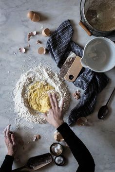 someone is kneading dough into a bowl on a table with other ingredients and utensils