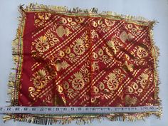 a red and gold cloth with fringes on it