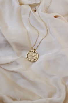 A gold rotating necklace which features the face of the sun on one side and the face of the moon on the other. Comes in 2 sizes. Small charm is 1” wide and hangs from a 16” chain Big charm is 1.5” wide and hangs from a 21” chain Silver Sun And Moon Design Gold-plated Necklace, Celestial Round Locket Necklace, Gold Necklace With Oval Moon Charm Pendant, Gold Oval Pendant Necklace With Moon Charm, Moon Phase Coin Necklace With Round Pendant, Gold Moon Charm Necklace With Sun And Moon Design, Celestial Pendant Charm Necklace With Adjustable Chain, Celestial Style Necklace With Large Round Pendant, Celestial Necklace With Large Round Pendant