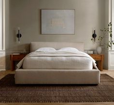 a large bed sitting on top of a wooden floor next to a wall mounted painting