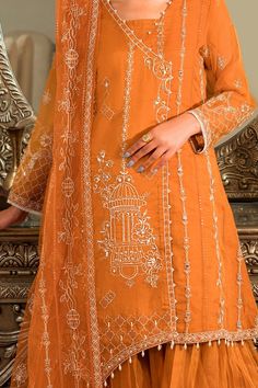 Rust Orange Heavily Embellished Kameez Sharara Pakistani Party Dress comes with the quintessential silhouette that "Floral Grid" embodies, the short angrakha shirt which is crafted on a rust orange organza fabric. The shirt is decorated with thread embroidery with pearl, sequin and adda embellishments on the front. It is paired with flared pleated sharara topped with thread embroidered net dupatta. Embroidered Net Kameez: The beautiful kameez in an alluring pink color is adorned with shimmering Anarkali Cambric Kurta For Party, Elegant Cambric Anarkali Set For Navratri, Festive Party Kurta In Cambric, Festive Cambric Kurta For Party, Elegant Cambric Sharara For Festive Occasions, Diwali Cambric Dresses With Zari Work, Festive Dresses With Dabka In Cambric, Festive Dresses In Cambric With Dabka Detail, Elegant Cambric Traditional Wear For Navratri