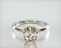 a yellow gold engagement ring with a round cut diamond in the center, on a white background