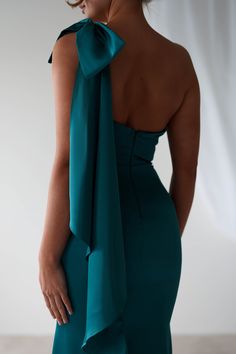 the back of a woman wearing a green dress with a large bow on her shoulder