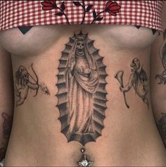 a woman's stomach with tattoos on it and an image of the virgin mary