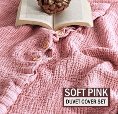 an open book sitting on top of a pink blanket