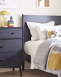 a child's room with a bed, dresser and toy bear on the nightstand