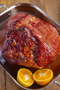 a large piece of meat sitting in a pan next to sliced oranges