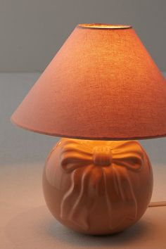 a lamp that is sitting on the floor next to a light fixture with a red shade