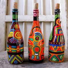 three colorful painted bottles sitting on top of a wooden table