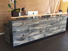 a man sitting at a desk in front of a laptop computer on top of a wooden counter