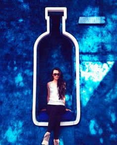 a woman sitting on top of a toilet seat in front of a blue wall with the words absolut