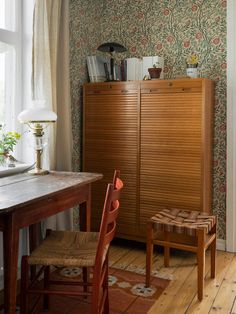 a room with a wooden table and chair next to a cabinet in the middle of it