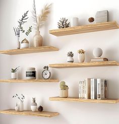 three wooden shelves with plants, books and other decorative items on them against a white wall