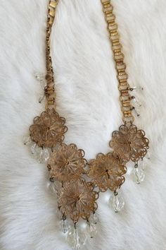 "This is a vintage 1920s-1930s statement necklace. The gold tone metalwork is very intricate and is in a round filigree design. There is one visible area of tarnish (pictured) from wear and age. The necklace has a unique chain and crystal tone details. All of the crystal tone gems are in excellent condition. Overall this necklace is in great condition. Measurements: Length: 9.5\" | Length of detail: 2.5\" Unless otherwise stated all vintage items are used and may have minor to moderate wear or d Victorian Filigree Metal Necklaces, Victorian Filigree Metal Necklace, Elegant Brass Necklace With Intricate Design, Ornate Bridal Necklace With Intricate Design, Wedding Filigree Metal Necklaces, Vintage Gold-tone Metal Jewelry, Vintage Gold Metal Jewelry, Antique Gold Jewelry For Vintage Events, Antique Gold Brass Filigree Jewelry