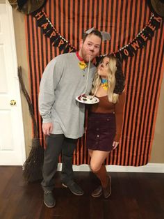 a man and woman posing in front of a halloween banner