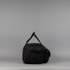 a black duffel bag sitting on top of a white table next to a gray wall