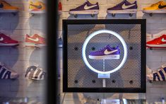 a display case with various shoes on it in front of a wall full of sneakers