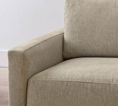 a close up view of the back end of a beige couch with wood flooring