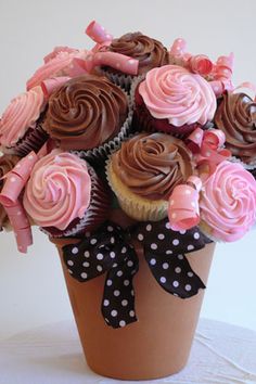 a cupcake bouquet in a vase with pink and brown frosting on it's sides