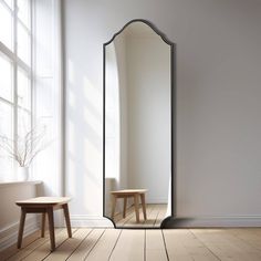 a large mirror sitting on top of a wooden floor next to a table and chair