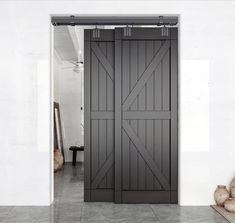 an open barn door in a white room with gray tile flooring and large wooden doors