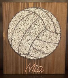 a wooden plaque with a white ball on it and the word mia written in cursive writing