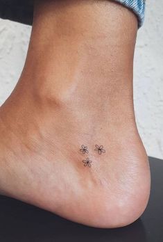 a small tattoo on the foot of a person with three flowers in front of them