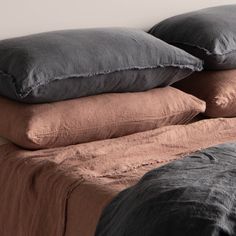 two pillows are stacked on top of each other in front of a bed with brown sheets