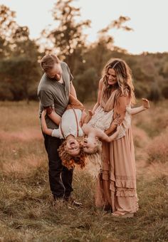 three people standing in a field with one holding the other's head and laughing