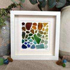 a white frame holding a multicolored sea glass mosaic