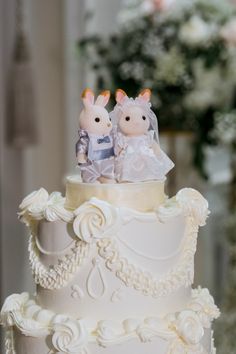 a wedding cake with two stuffed animals on top