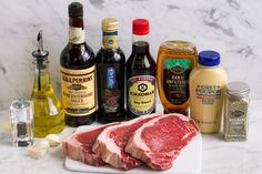 raw meat on a cutting board surrounded by condiments and seasonings for cooking