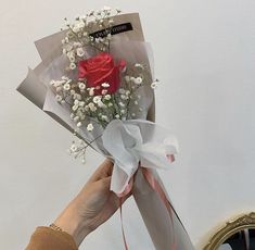 a person holding a bouquet of flowers in front of a mirror with a red rose on it