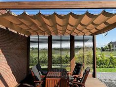 an outdoor covered patio with wooden furniture and shades on the top part of the pergolated roof