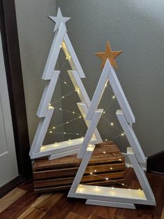 a christmas tree made out of plywood with lights on the bottom and stars at the top