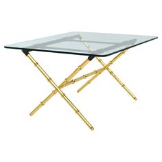 a glass table with gold metal legs and a square glass top on an isolated white background