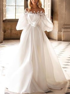 a woman in a white wedding dress standing on a checkered floor with an open window behind her